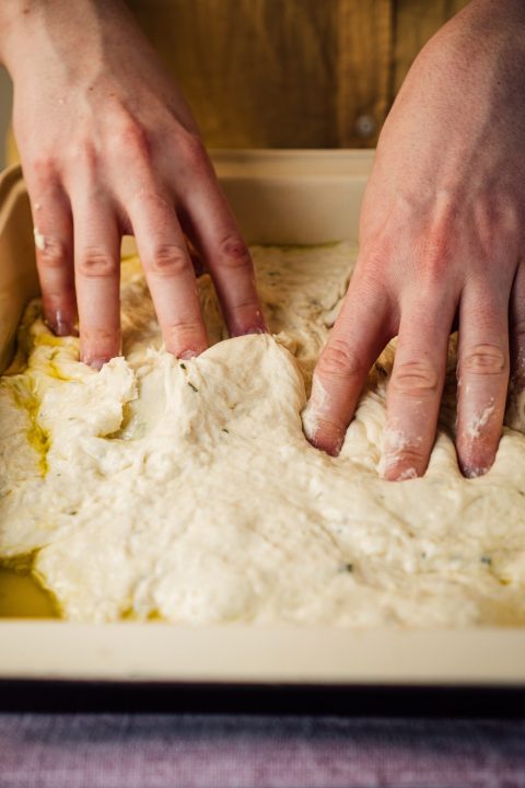 Person holding sourdough dough on white table