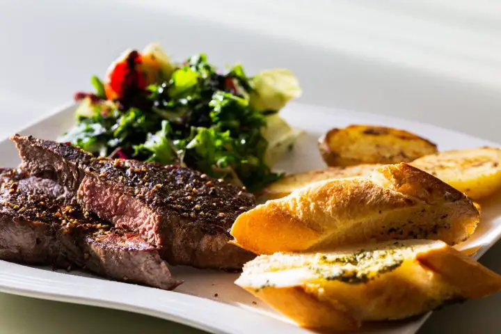 Medium rare rump steak with salad, potatoes and baguette slices